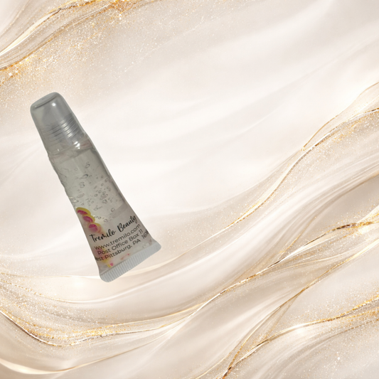 Pink Lemonade Kiss™ lip gloss standing on light marble-gold background, showing floating pink lemon slice charms inside