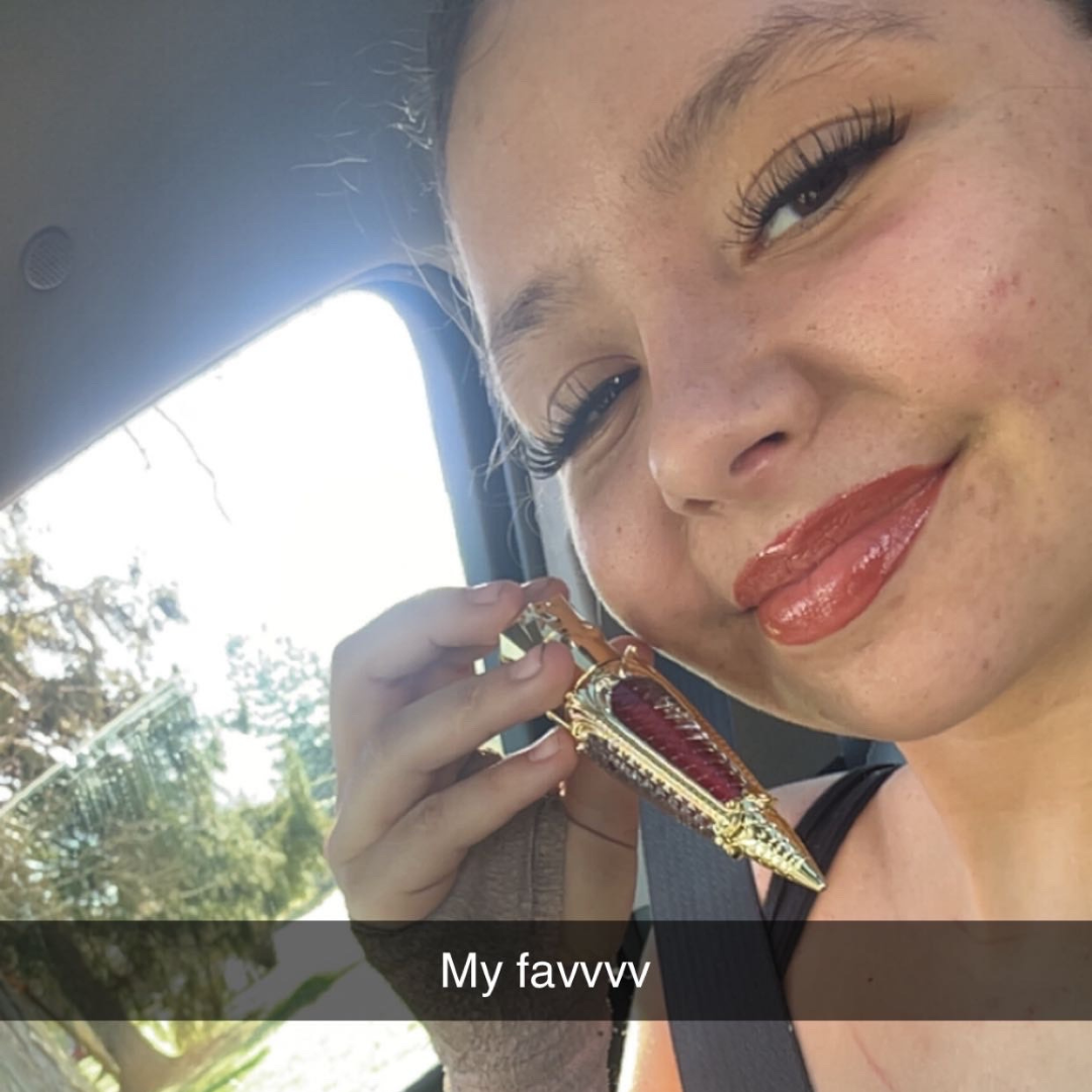 Woman applying Steelheart lip gloss by Tremilo Beauty with bold red glossy finish in natural lighting