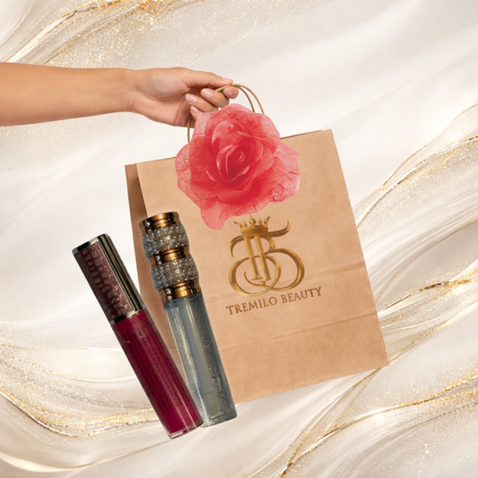 Tremilo “Oh Crap — Better” gift bundle showing a kraft paper shopping bag with rose accent and two Tremilo lip glosses on a swirled marble background.