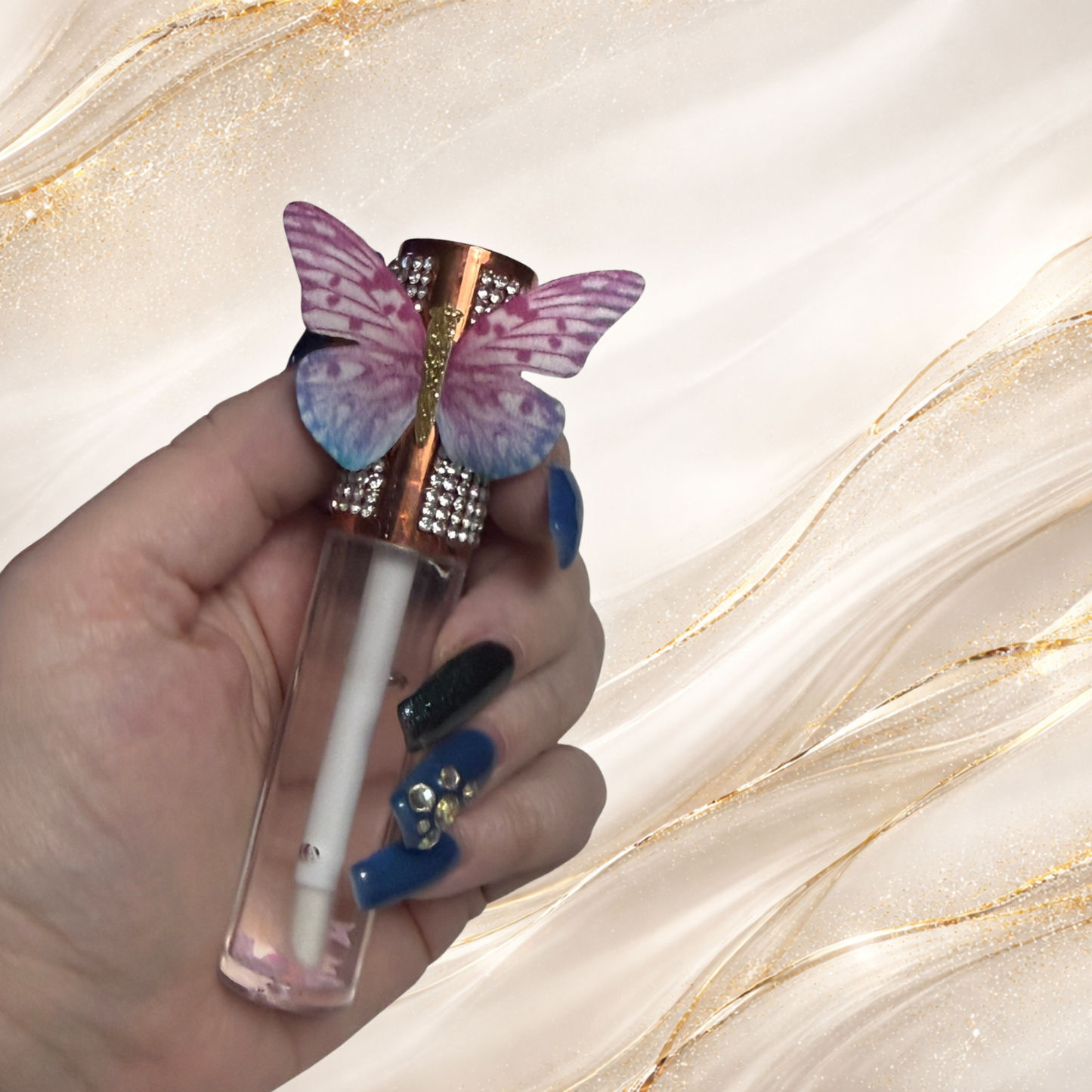 Flutterlight clear lip gloss with butterfly charm cap held in hand – Tremilo Beauty gloss with suspended star charms.