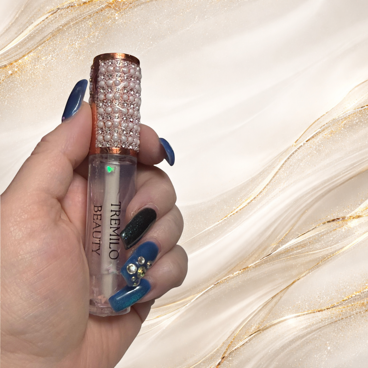 Flutterlight clear lip gloss held in hand showing suspended star charms and decorative pearl cap.