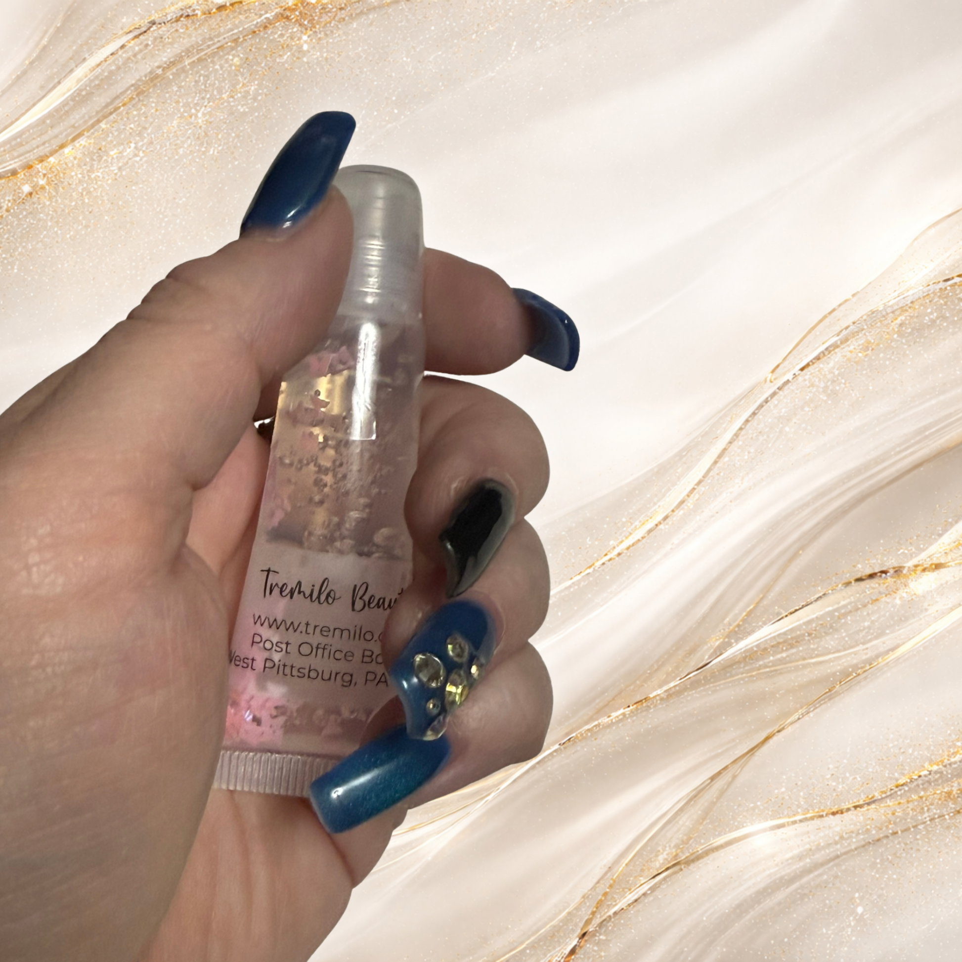 Hand holding Flutterlight Gloss™ 10 ml squeeze tube with floating butterfly accents