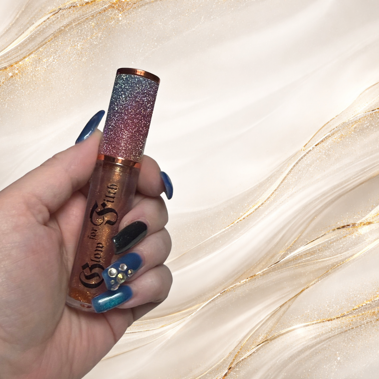 GILTTRIP™ gold shimmer lip gloss held in hand showing luminous metallic sparkle by Glow for Filth.