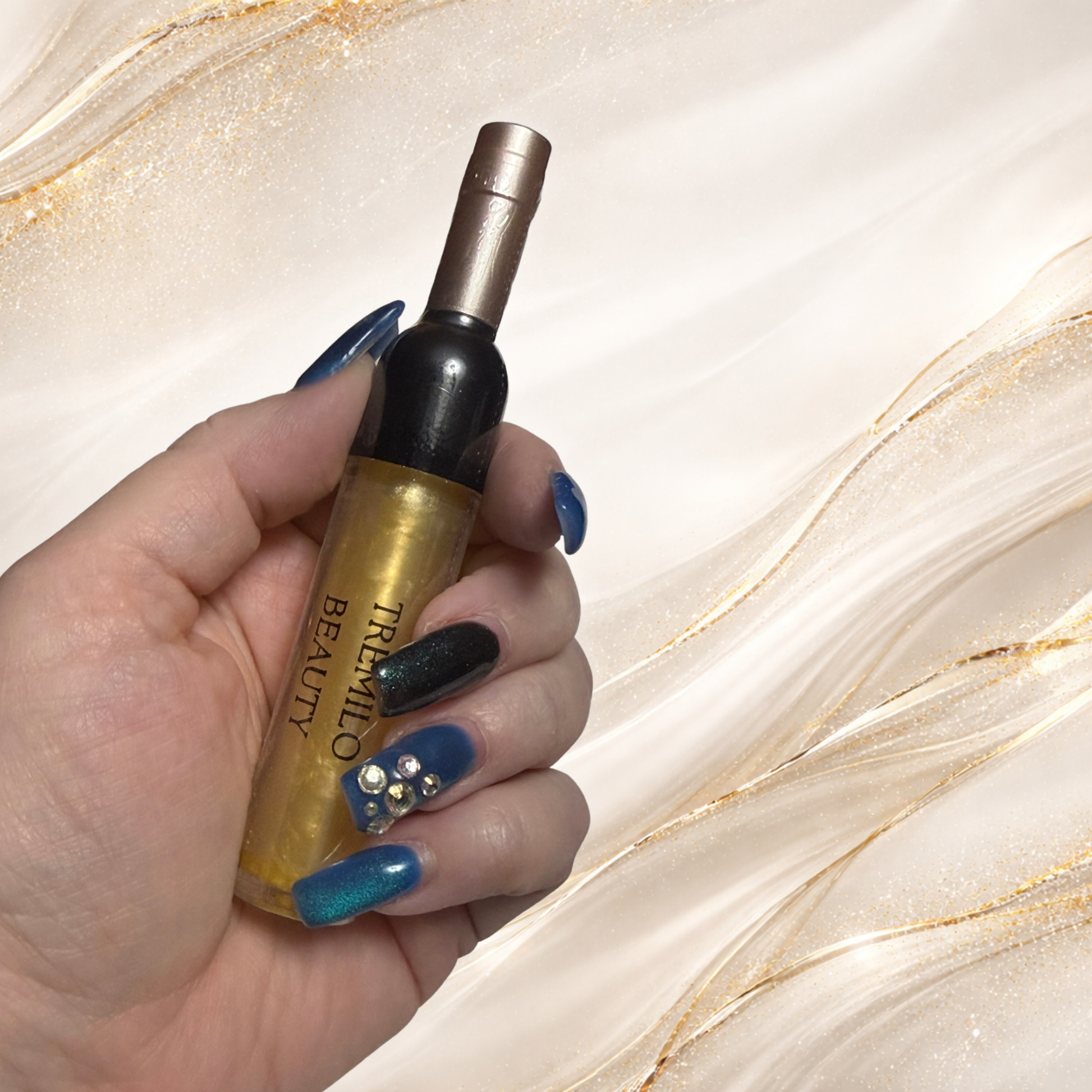 Steel City Gold lip gloss held in hand featuring gold shimmer gloss in wine bottle style packaging.