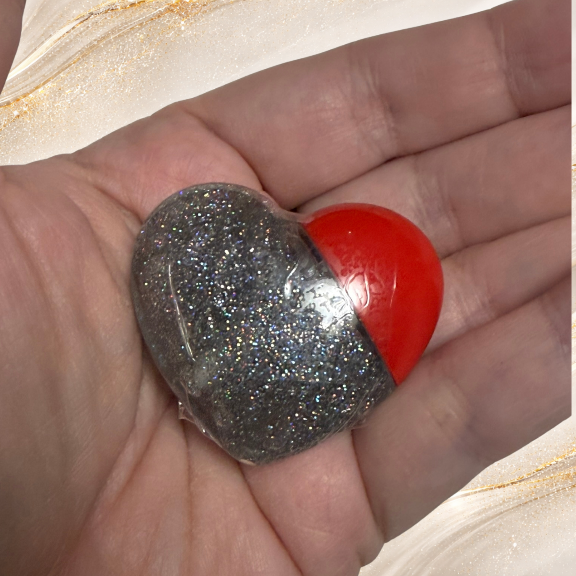 Tremilo Riveting lip gloss in heart tube held in hand showing black glitter gloss and red heart cap