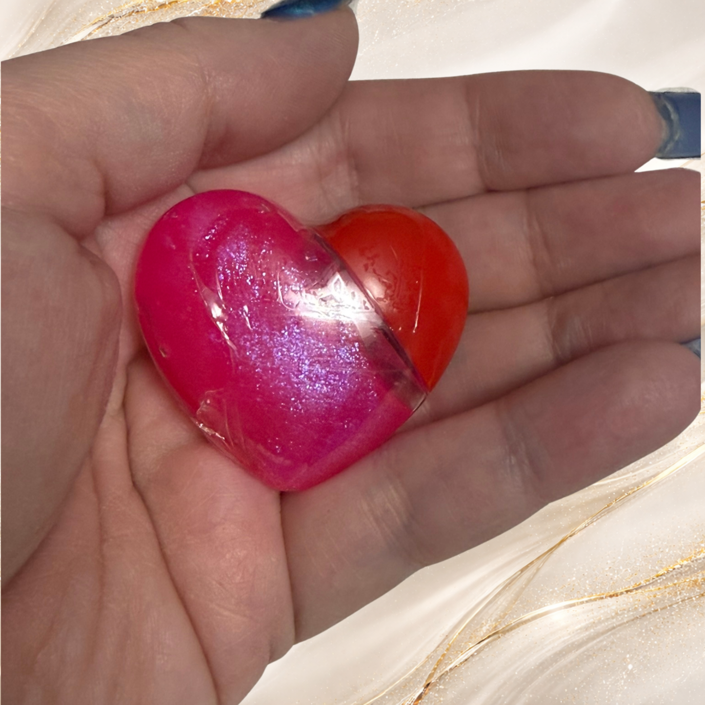 Tremilo South Side Pop lip gloss in heart-shaped tube held in hand showing vibrant pink shimmer gloss and red heart cap