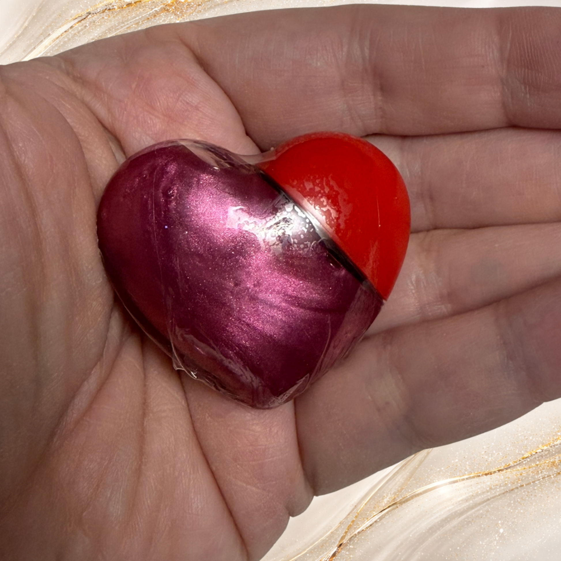 Three Rivers Rose lip gloss from Tremilo Beauty held in hand in heart shaped container with rose pink shimmer gloss