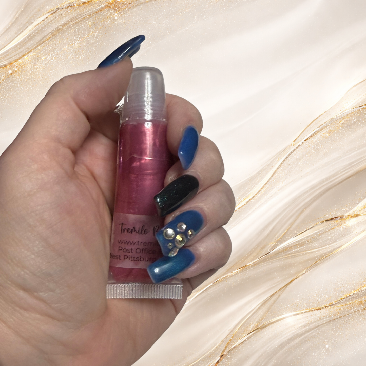 Three Rivers Rose lip gloss from Tremilo Beauty held in hand in squeeze tube showing rose pink shimmer gloss