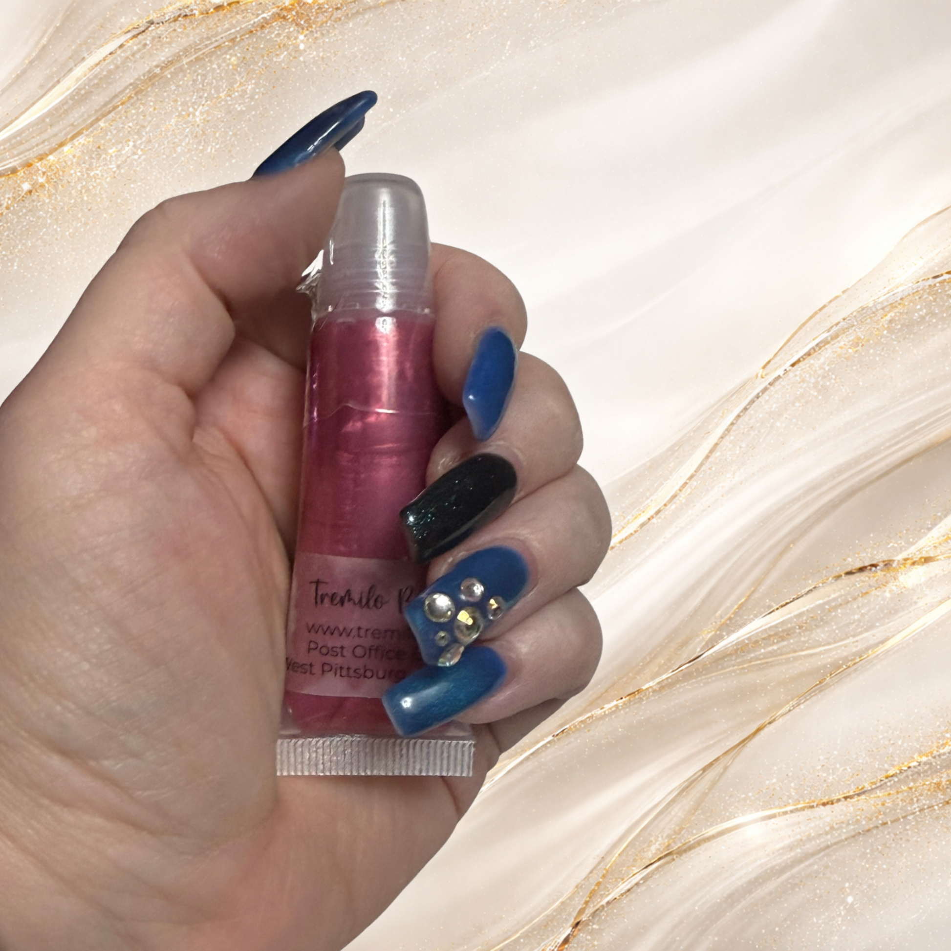 Three Rivers Rose lip gloss from Tremilo Beauty held in hand in squeeze tube showing rose pink shimmer gloss